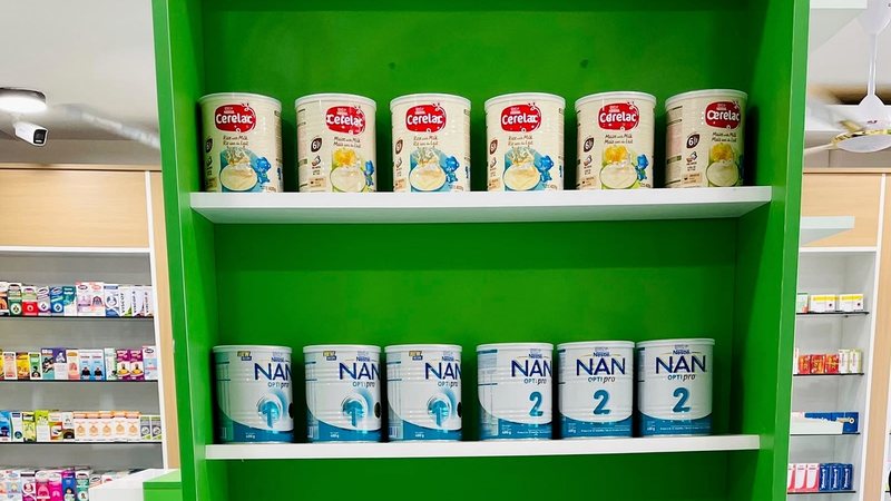 Infant formula and baby cereal tins on a Unihealth Pharmacy shelf.