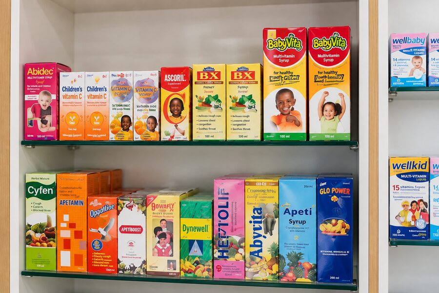 Cartons of family syrups and tonics lined up on the Unihealth Pharmacy shelves.